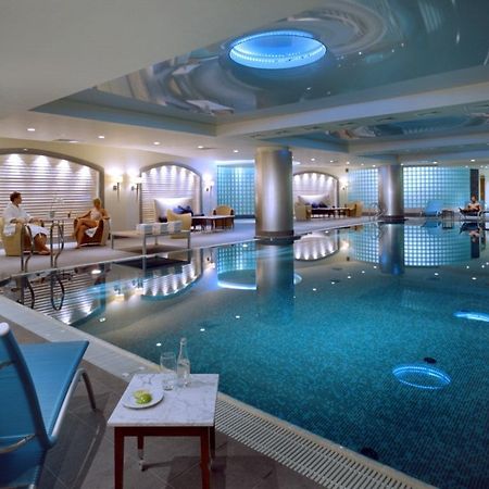 Regent Warsaw Hotel Facilități foto The photo shows a luxurious indoor swimming pool area. The pool has a sparkling blue water surface, and its surroundings are designed with sleek, contemporary architecture. The lighting is soft, with blue accents illuminating the space. On one side, 