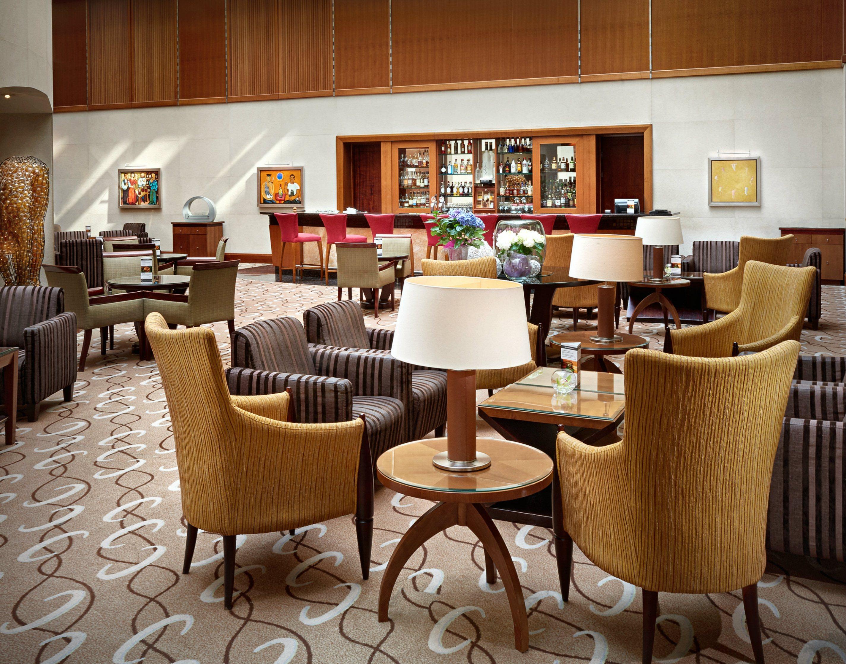 Regent Warsaw Hotel Exterior foto The photo shows a stylish and modern lounge area, likely within a hotel or upscale establishment. The seating consists of several chairs, predominantly in shades of brown and gold, arranged around small tables. A few lamps are placed on the tables, p