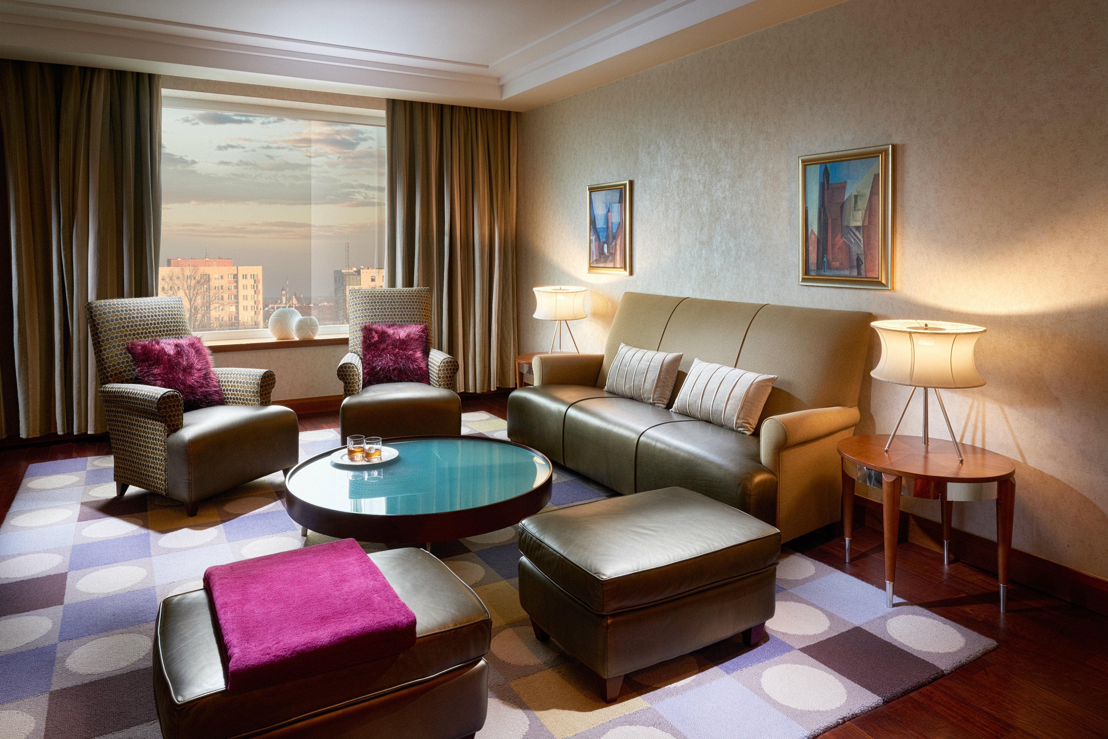 Regent Warsaw Hotel Exterior foto The photo shows a stylish and modern living room. It features a comfortable seating arrangement with a light brown leather sofa and two matching armchairs, each adorned with purple cushions. A round coffee table sits in the center, topped with a deco
