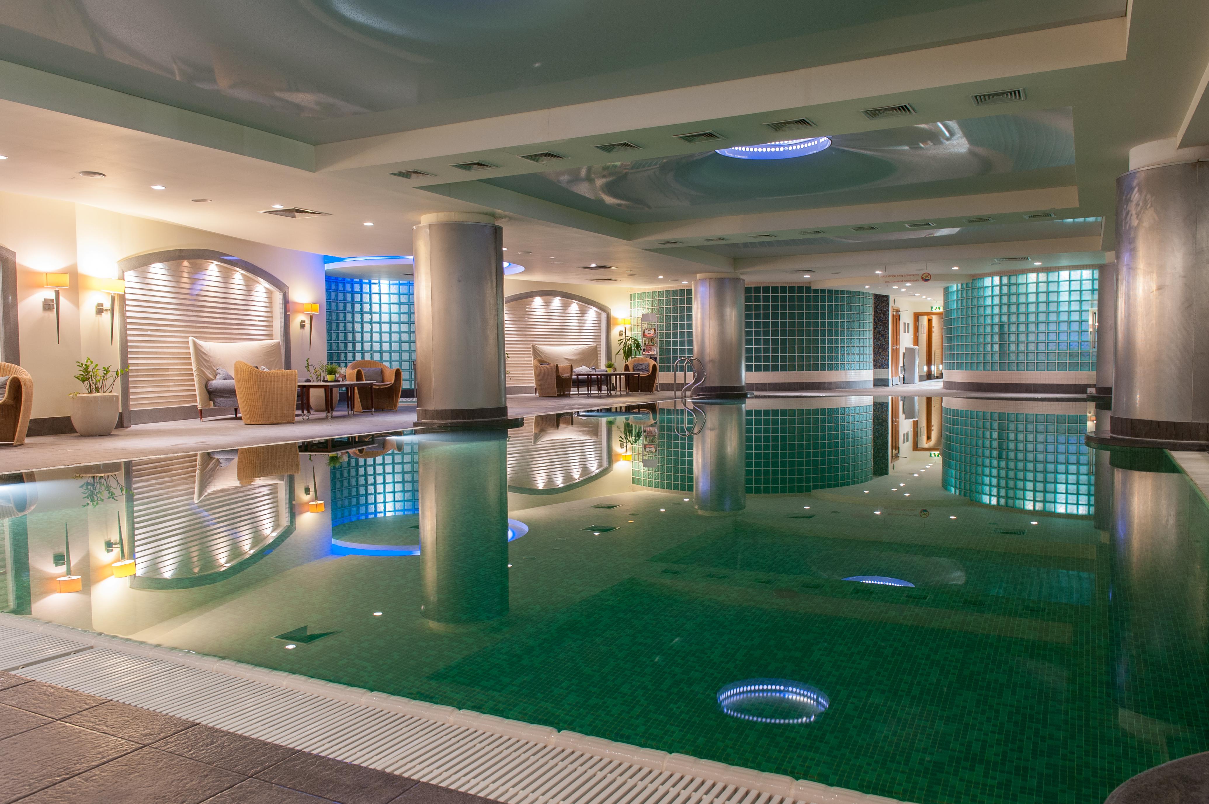 Regent Warsaw Hotel Exterior foto The image shows an indoor swimming pool area, featuring a sleek and modern design. The water appears calm and reflects the surrounding lighting. There are several columns, and the ceiling has a contemporary look with different light fixtures. The wal