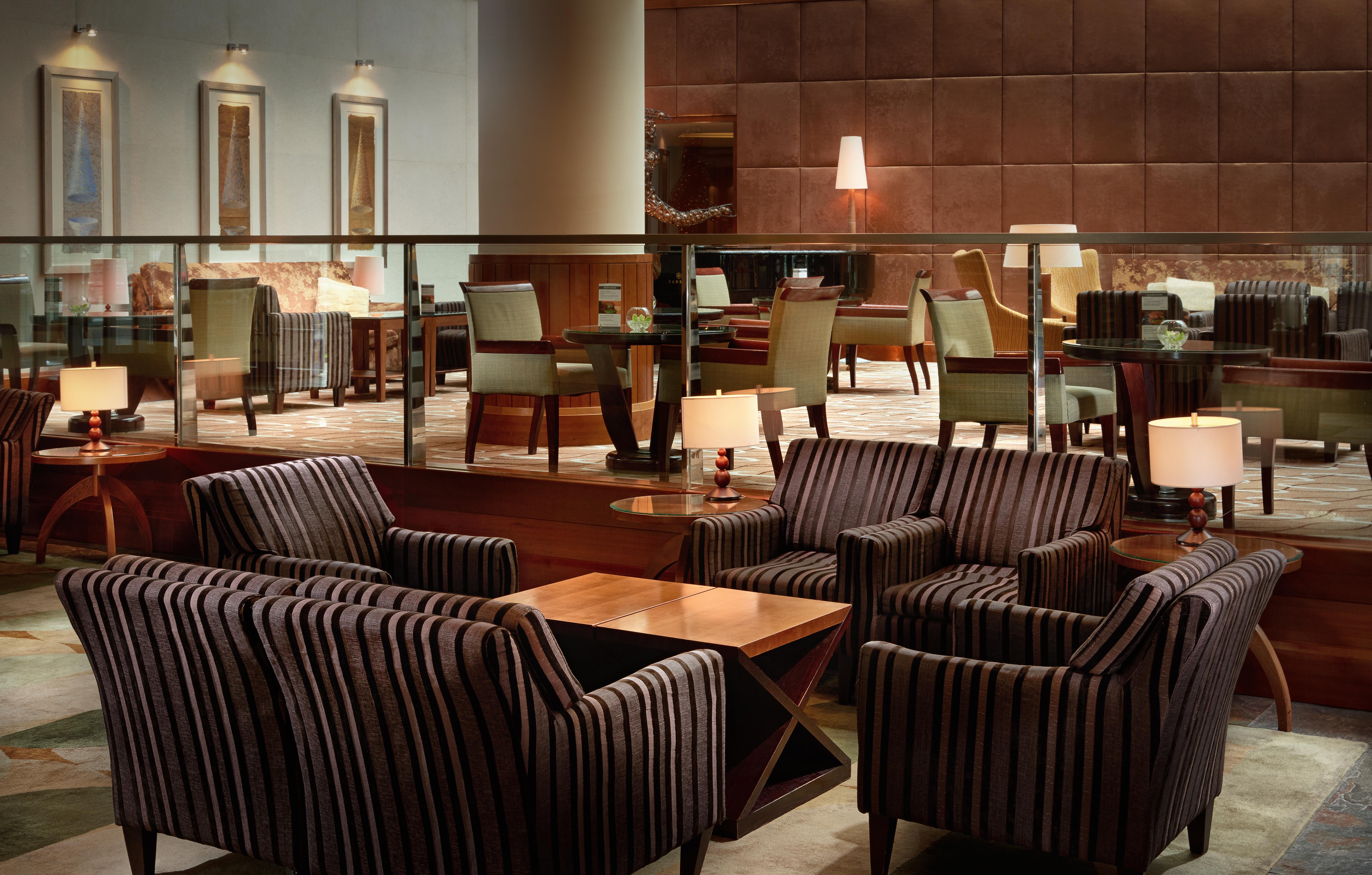 Regent Warsaw Hotel Exterior foto The photo shows a stylish and modern lounge area. There are several groups of upholstered chairs and couches, featuring a striped design. A wooden coffee table is placed in the center of the seating arrangement. The interior decor is sophisticated, w