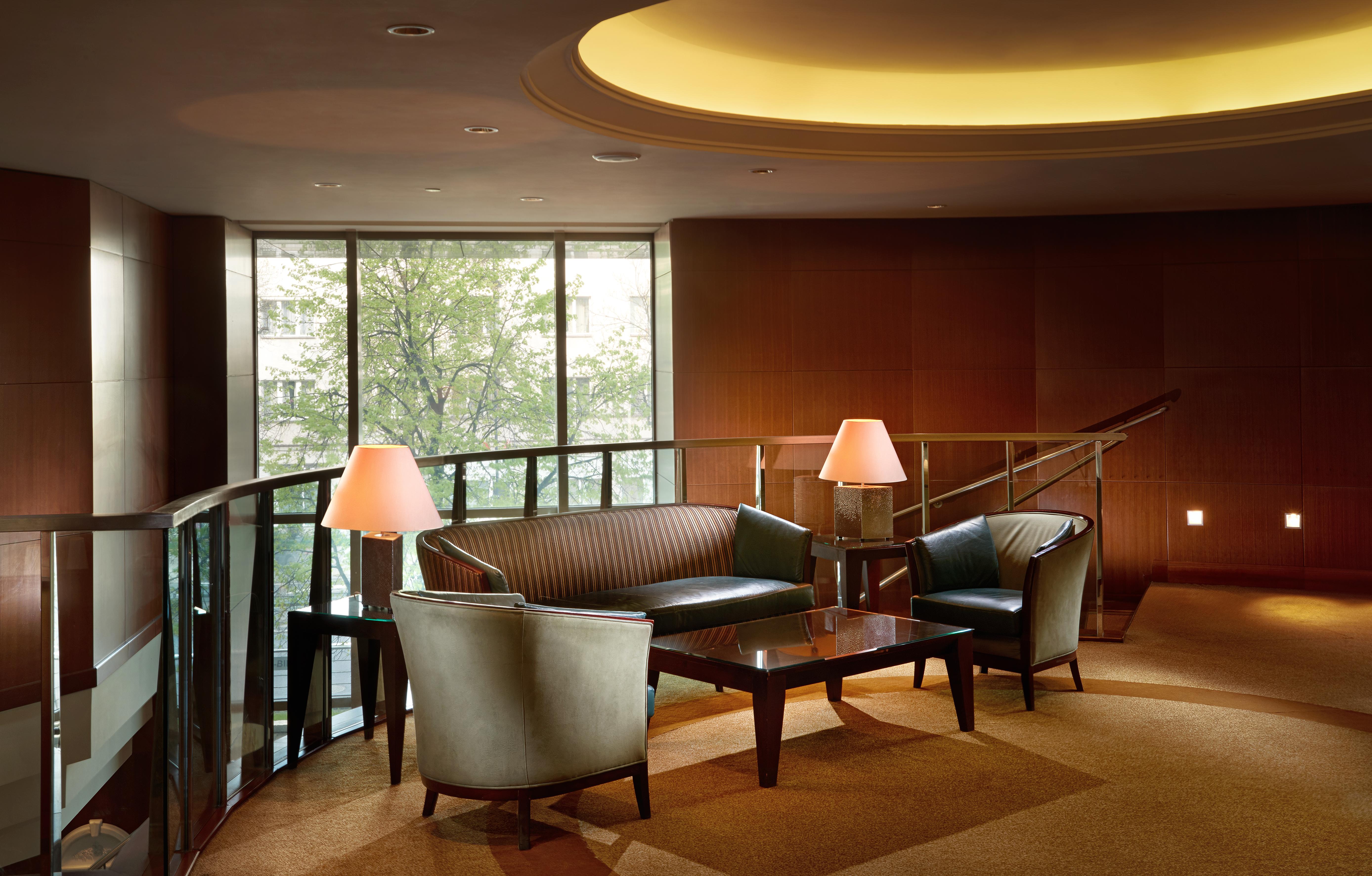 Regent Warsaw Hotel Exterior foto The photo depicts a modern lounge area. It features a curved seating arrangement with a dark, leather couch and two matching armchairs. A sleek coffee table is placed in the center, and there are two lamps providing soft lighting. The space is enhanc