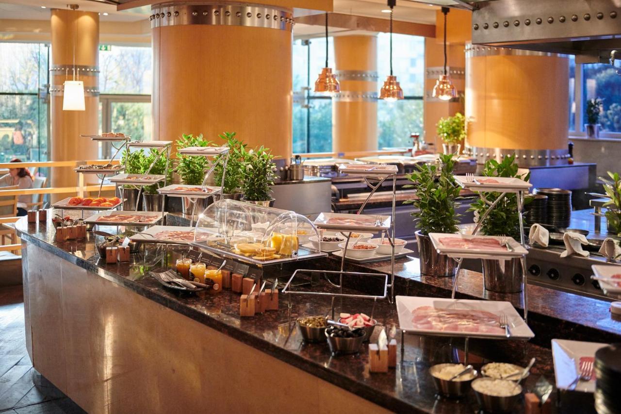 Regent Warsaw Hotel Exterior foto The photo shows a buffet setup in a restaurant or dining area. There is a long counter featuring various food items displayed in trays and covered with glass domes. The table is adorned with small potted plants, adding a touch of greenery to the spac
