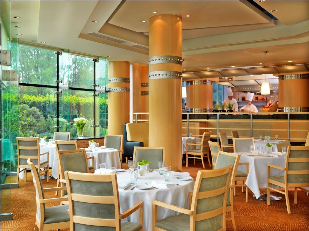 Regent Warsaw Hotel Exterior foto The photo shows an elegant restaurant interior. It features stylish wooden chairs around neatly set tables, which are adorned with white tablecloths and glassware. Large windows allow natural light to fill the space, providing a view of the greenery 