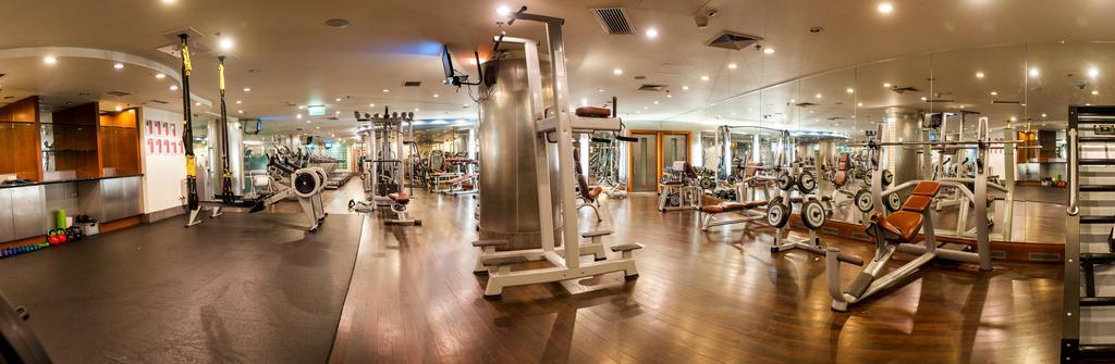 Regent Warsaw Hotel Exterior foto The photo shows an interior gym facility equipped with various exercise machines and weights. The space features a wooden floor and is well-lit, with overhead lighting and large mirrors on the walls. In the foreground, there is a multi-use exercise m