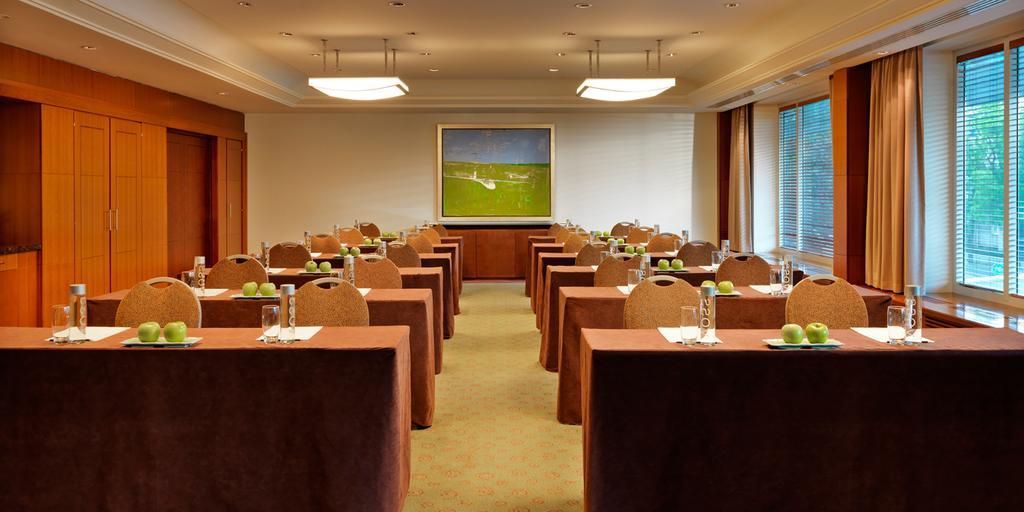 Regent Warsaw Hotel Exterior foto The photo shows a conference room set up for a meeting or seminar. There are several tables arranged in a row, each covered with brown tablecloths. Each table is equipped with notepads, pens, bottled water, and green apples. The room has a bright atm