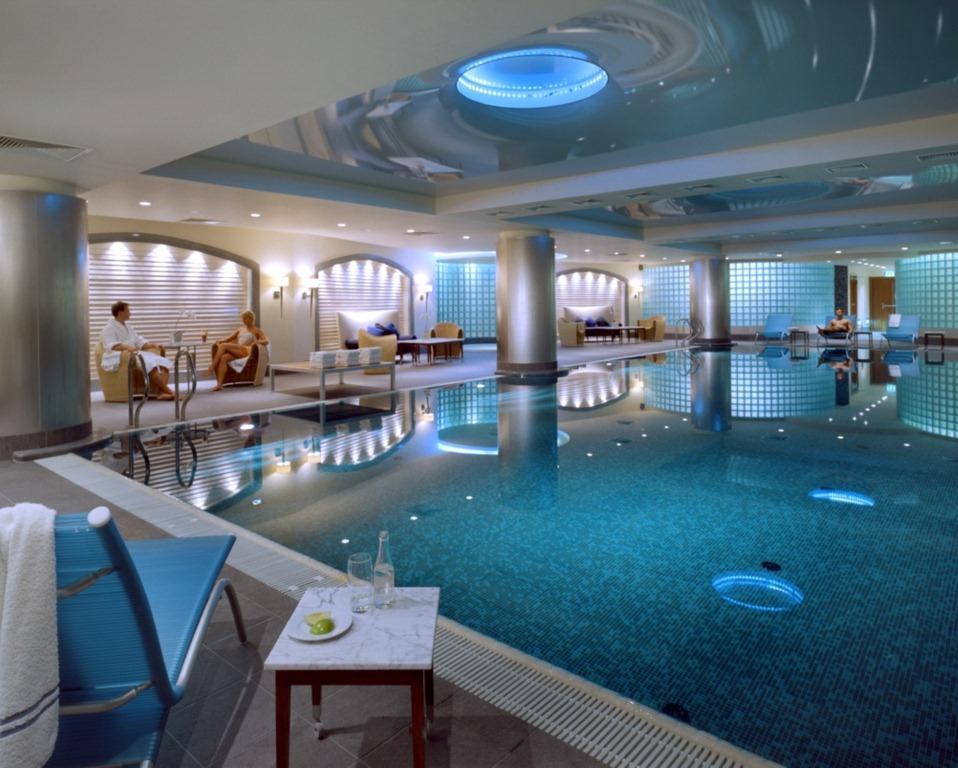 Regent Warsaw Hotel Facilități foto The photo shows a luxurious indoor swimming pool area. The pool has a sparkling blue water surface, and its surroundings are designed with sleek, contemporary architecture. The lighting is soft, with blue accents illuminating the space. On one side, 