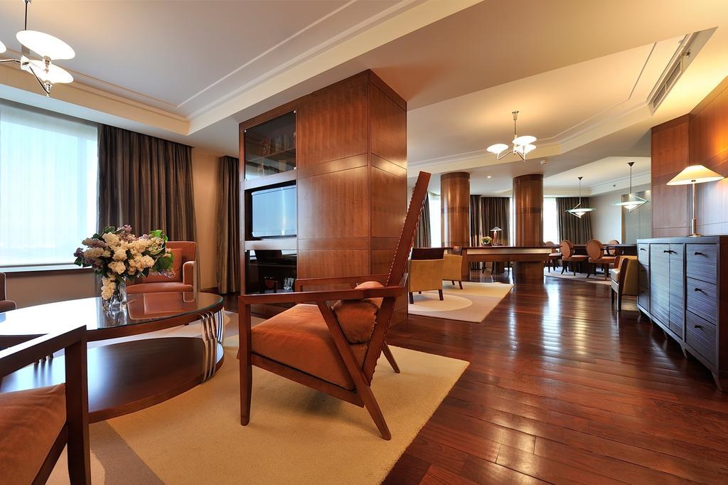 Regent Warsaw Hotel Exterior foto The photo shows a spacious and elegantly designed interior, resembling a well-furnished hotel suite or upscale living area. The room features hardwood floors, large windows with curtains, and multiple seating arrangements. In the foreground, there's 
