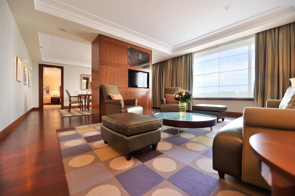 Regent Warsaw Hotel Exterior foto The photo shows a modern and stylish living room. It features a comfortable seating arrangement with several chairs and an ottoman arranged around a circular coffee table. The floor is covered with a patterned rug in various colors. A partition with 